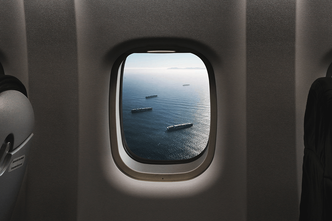 Navios cargueiros sendo vistos através de uma janela de avião, representando processos de logística de transporte e armazenamento